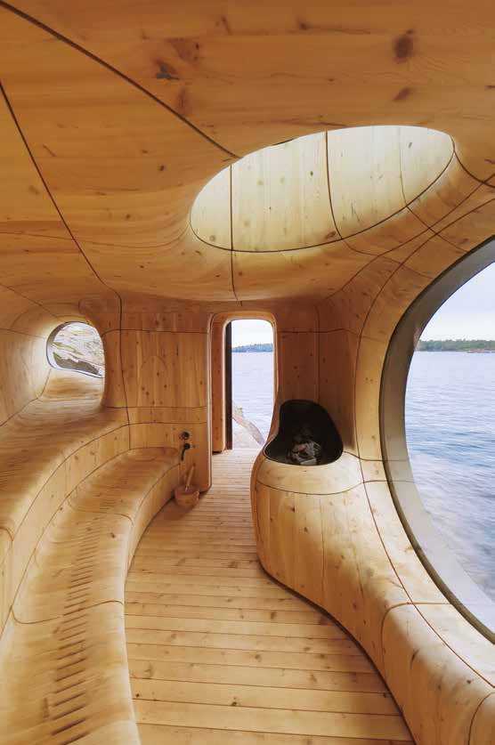 The sculpted cedar chamber of the Grotto Sauna, its curved walls and benches running unbroken into a great oval window onto Georgian Bay.